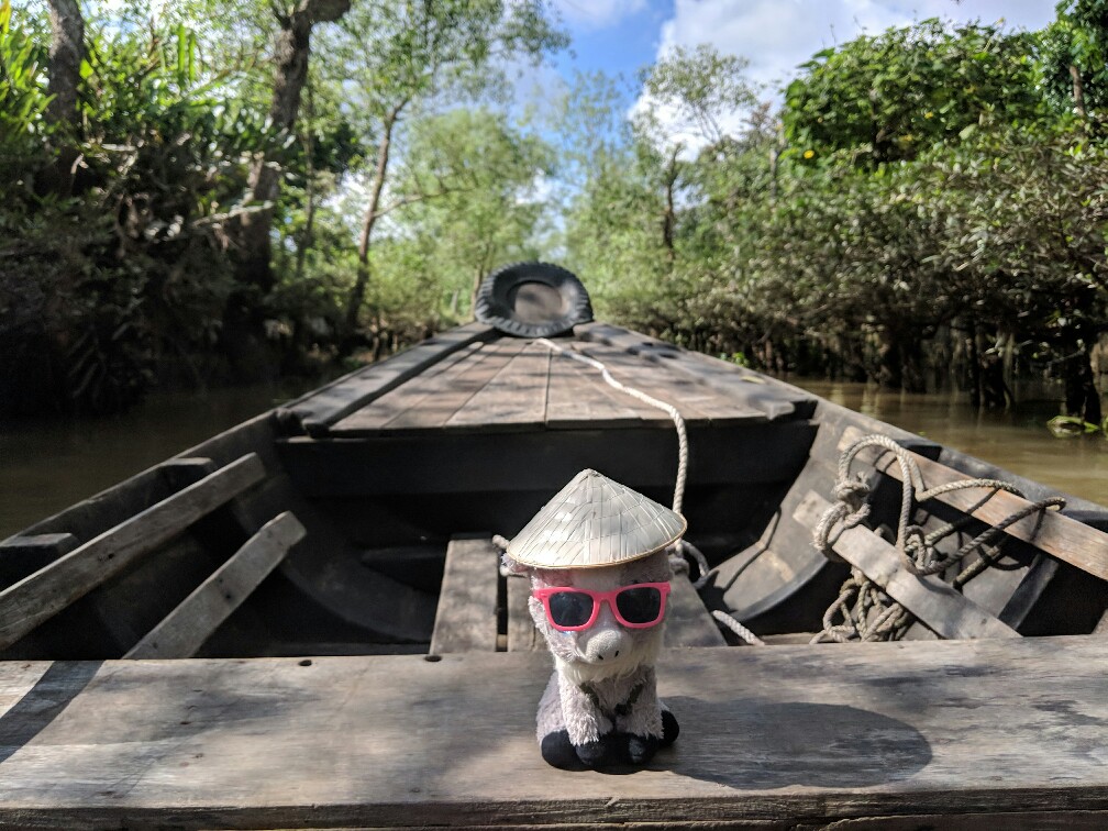 Peluche de Biquette sur la barque dans la jungle du Mekong au Vietnam
