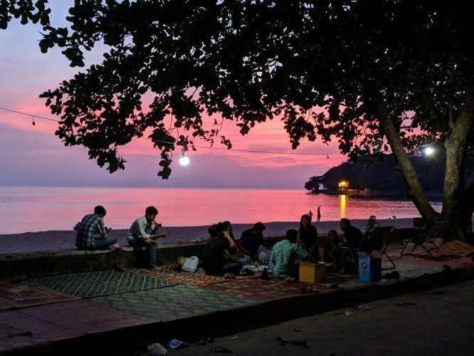Famille pique-niquant au coucher de soleil en bord de mer à Kep au Cambodge