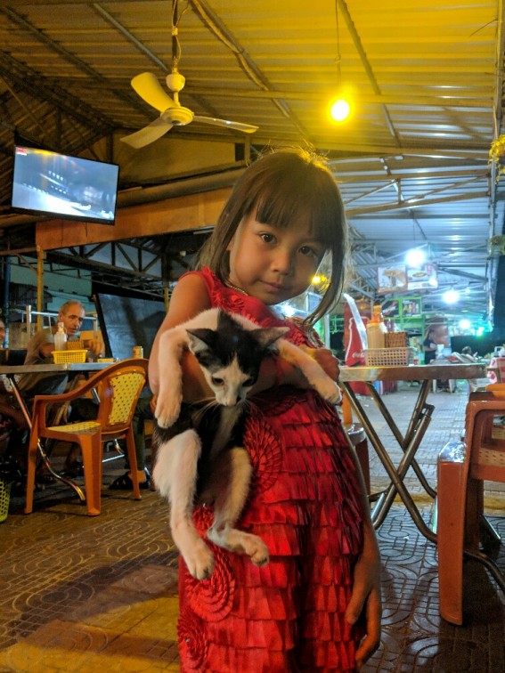 Portrait d'une fillette portant un chaton au marché de nuit de Kampong Cham, Cambodge