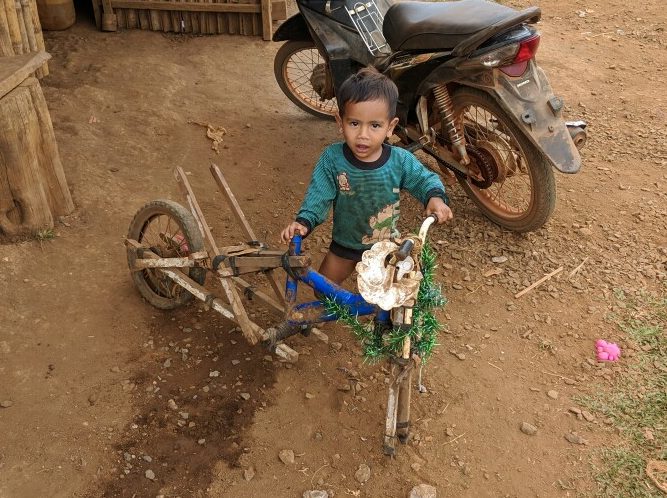 Enfant Bunong joue avec un vélo à moitié détruit, Cambodge