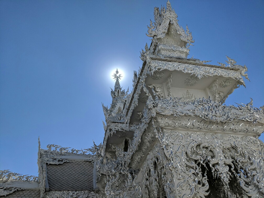 haut du temple blanc de Chiang Rai contrastant avec le bleu du ciel