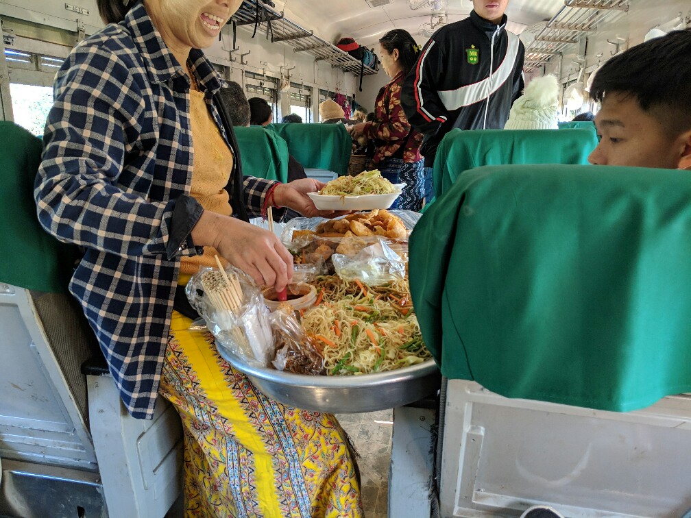 Vendeuse ambulante sert des nouilles à un client dans le train de Hsipaw en Birmanie