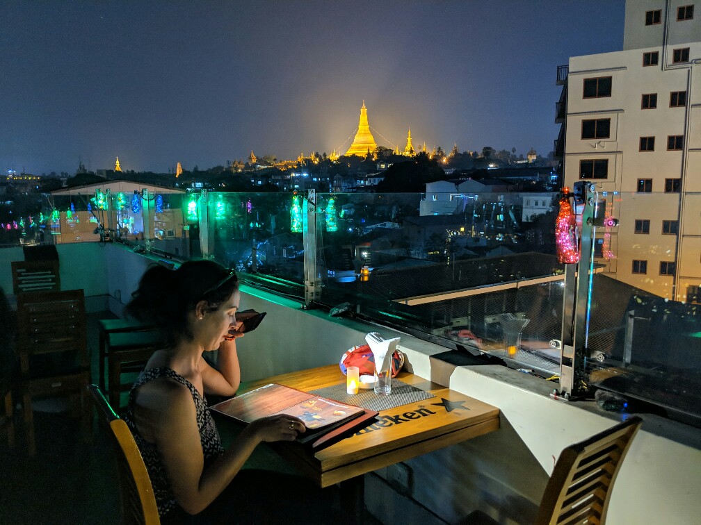 Salomé lisant le menu au rooftop du Vista Bar avec au fond la pagode Shwedagon