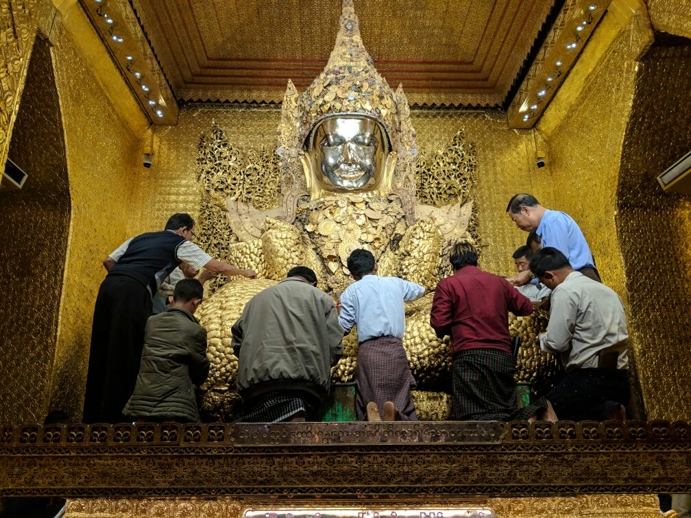 Statue de Bouddha se faisant couvrir de petites feuilles d'or au Temple de Mahamuni, Mandalay, Birmanie