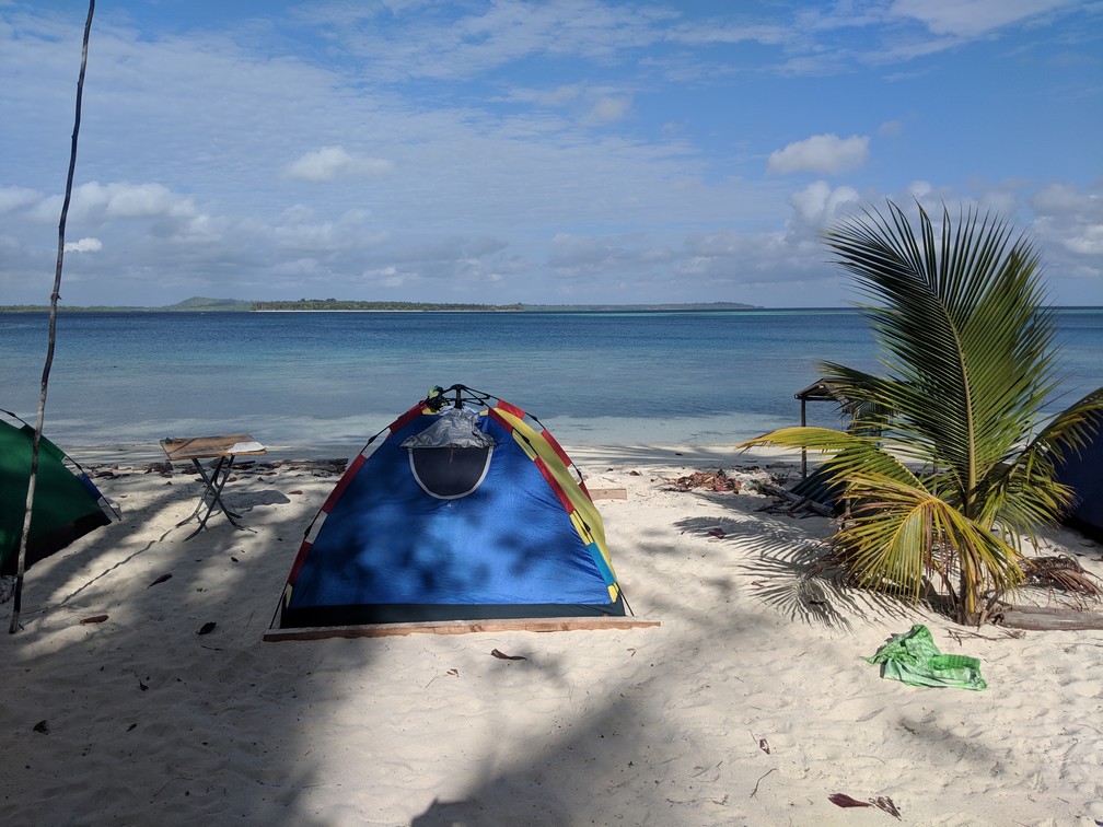 Tente installée sur la plage face à la mer turquoise