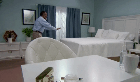Homme arrange l'oreiller du lit dans une chambre luxueuse