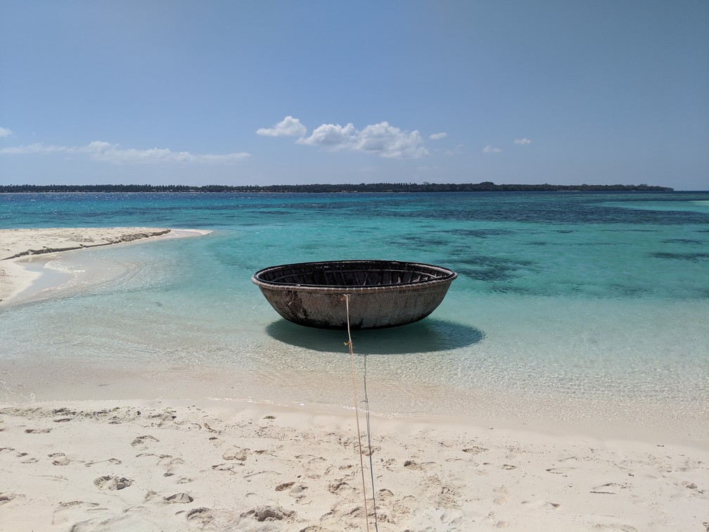 Bateau en forme de coquille de noix flotte au bord de l'eau turquoise près de l'île de Patawan