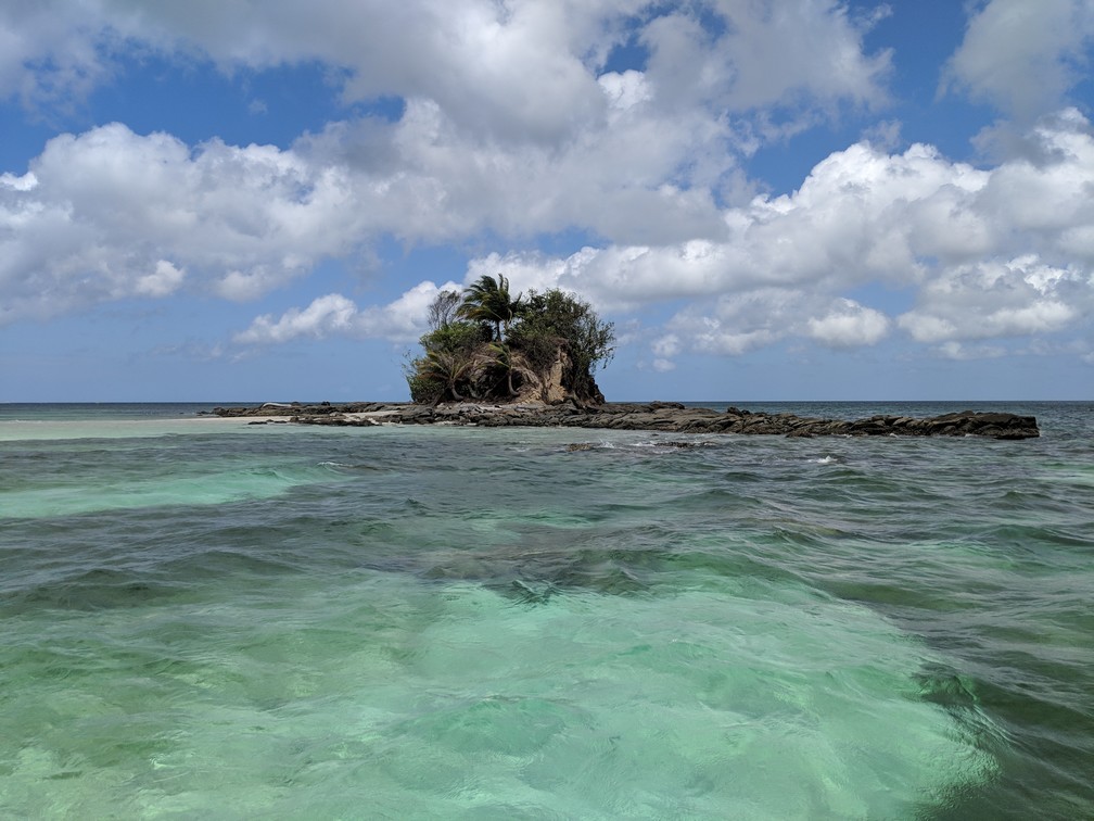 Petite île sans nom vue de loin entourée d'eau turquoise