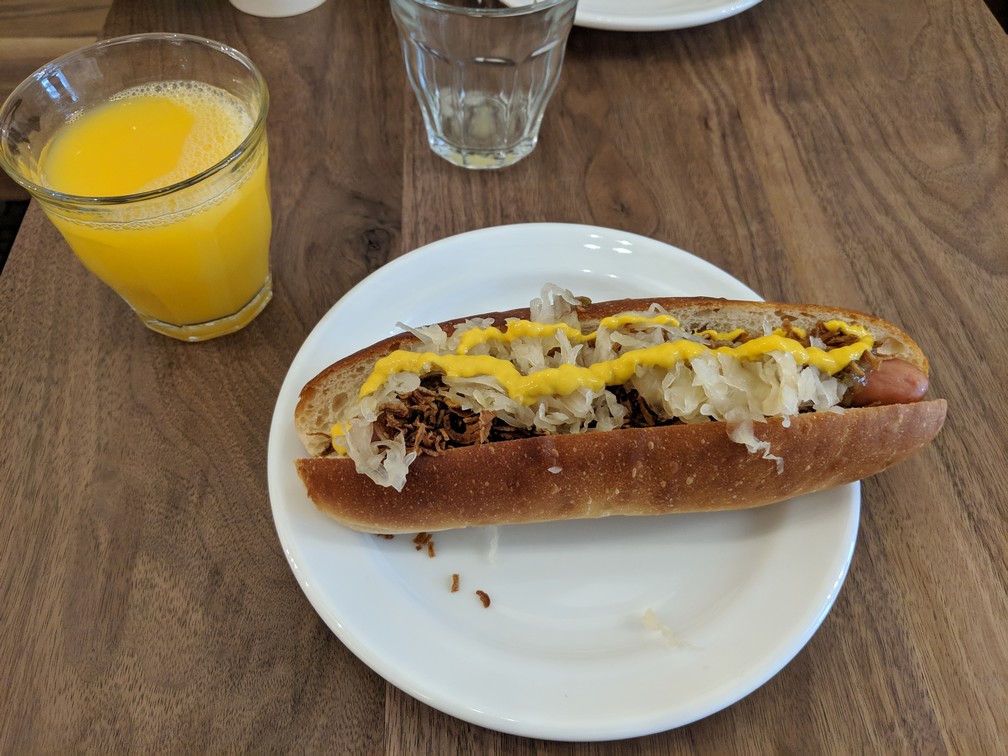 Un beau hotdog avec de la moutarde sur une assiette avec un verre de jus d'orange