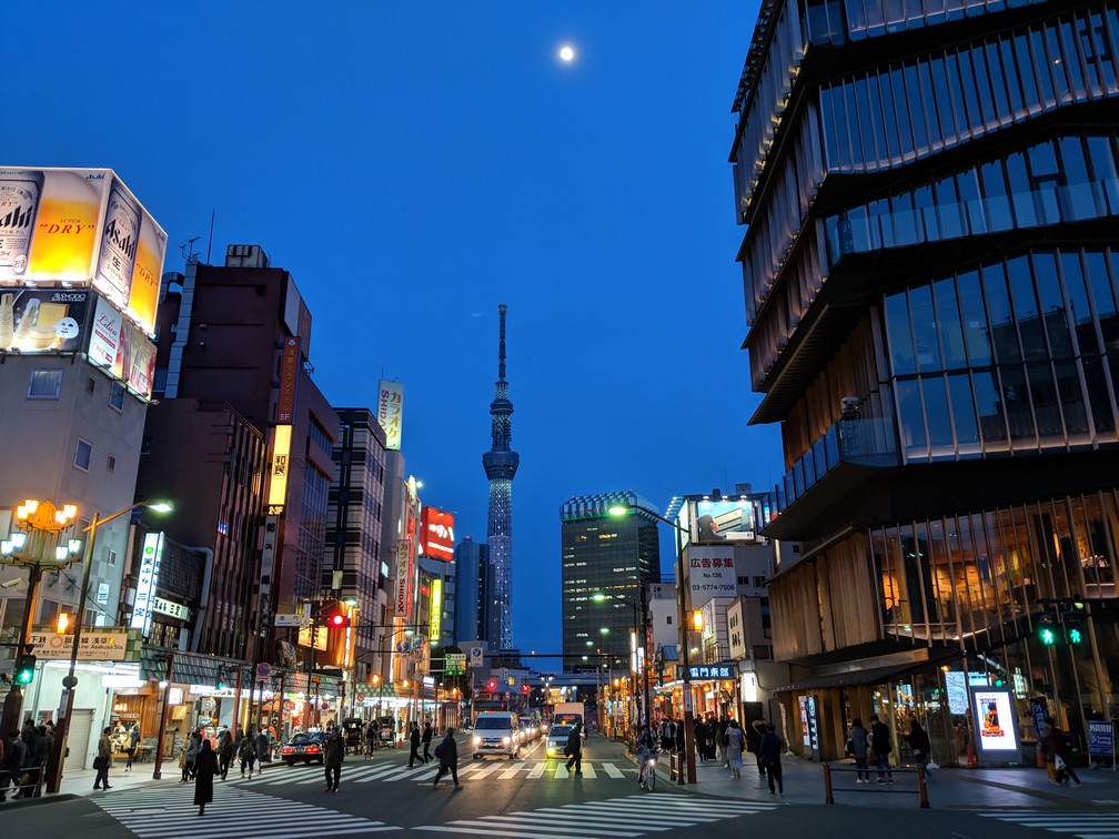 Un carrefour d'Asakusa de nuit, la Sky Tower au fond avec la lune au dessus
