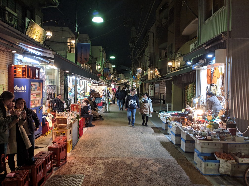 Une rue commercante éclairée par ses petites boutiques et fréquentée par quelques passants