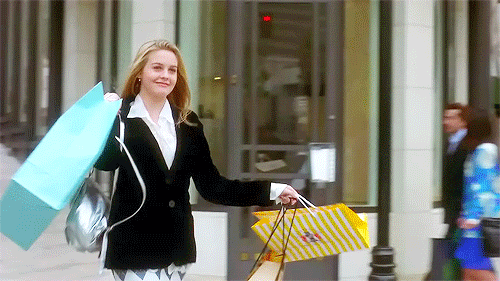 Une blonde souriante se balade avec de gros sacs de shopping