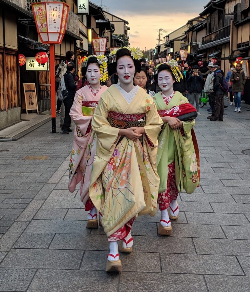 Trois Geishas marchent dans la rue, toute apprêtées