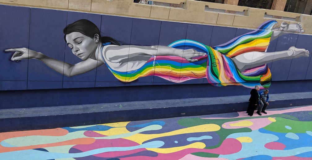 fresque murale représentant une jeune fille multicolore qui flotte à Santiago du Chili
