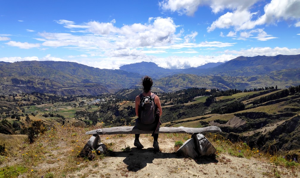 Salomé de dos, assise sur un banc et admirant la vue sur la campagne en Équateur  