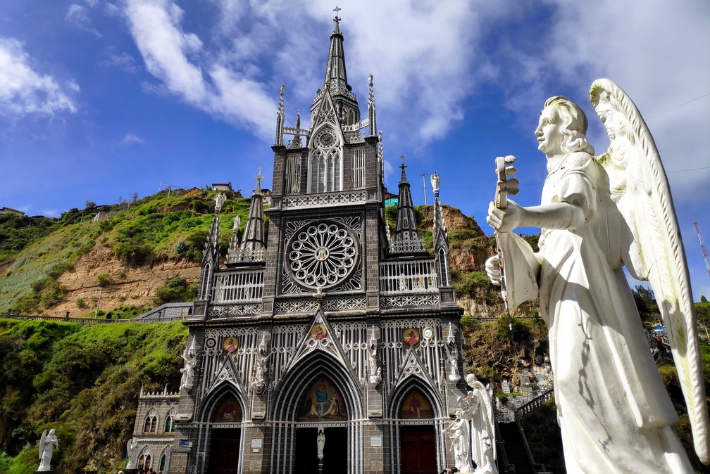 Église de Las Lajas à Ipiales avec une statue d'un ange blanc en premier plan