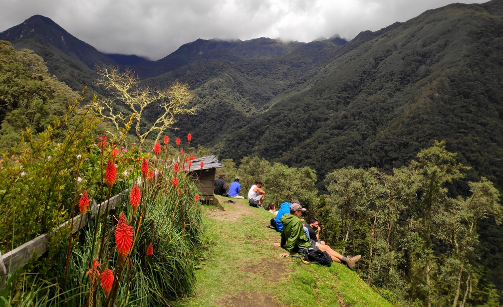 Vue sur les montagnes de la vallée de Cocora avec des randonneurs assis dans l'herbe au premier plan